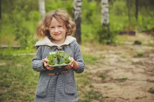 Criança segura suculentas ao ar livre, participando de uma atividade de artesanato para criança que envolve o cuidado com plantas e a criação de arranjos naturais de forma lúdica e educativa
