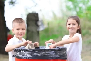 Crianças aprendendo sobre ecologia enquanto reciclam papel e plástico, contribuindo para o cuidado com o planeta.