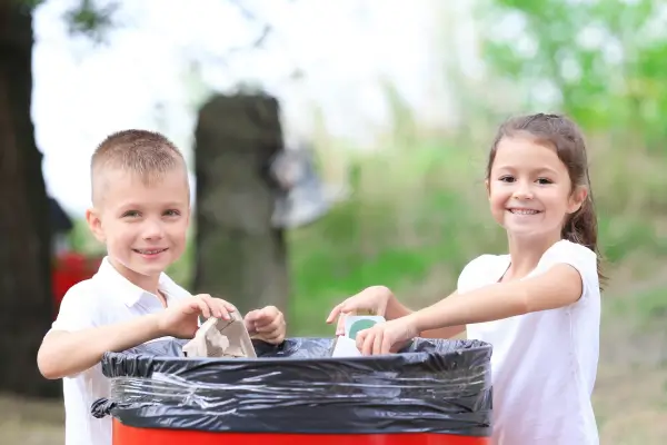 Crianças aprendendo sobre ecologia enquanto reciclam papel e plástico, contribuindo para o cuidado com o planeta.
