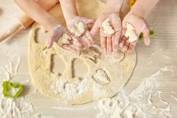Crianças moldam e decoram biscoitos em formato de animais durante uma atividade divertida na cozinha, aprendendo receitas criativas e lúdicas.