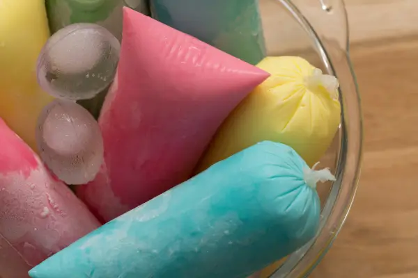 Vários sorvetes no saquinho dispostos sobre uma superfície colorida, representando receitas simples e refrescantes feitas com ingredientes naturais e acessíveis.