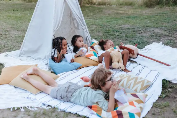 Crianças aproveitando um acampamento no quintal, com barraca montada para e muita diversão ao ar livre, vivendo momentos de aventura e imaginação em um ambiente familiar.