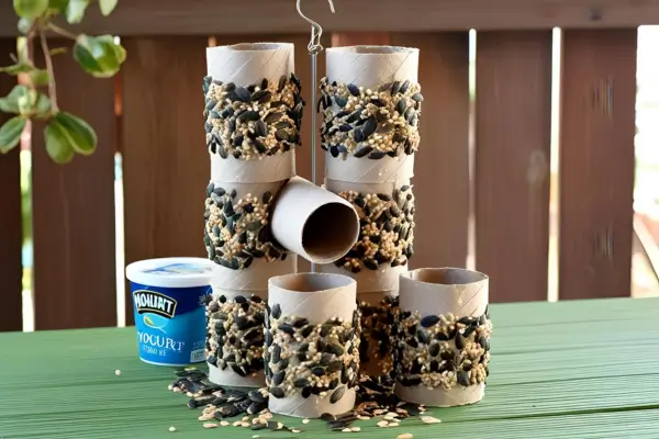 Comedouro para pássaros feito com rolo de papel e sementes, como parte de projetos sustentáveis com materiais recicláveis.