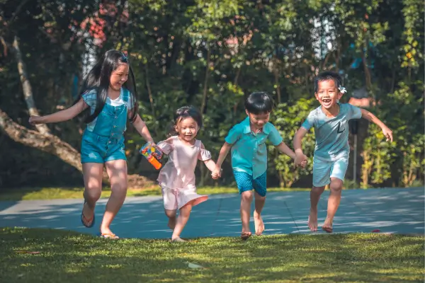 Crianças brincando e explorando um jardim, envolvidas em atividades que estimulam a criatividade em contato com a natureza