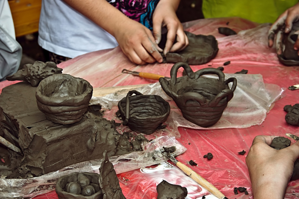 Crianças modelando esculturas com argila, explorando formas e texturas em uma atividade de artesanato para crianças que estimula a imaginação e o desenvolvimento sensorial
