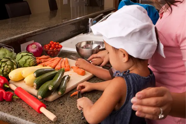 Mãe e filho pequenos cozinhando juntos na cozinha, preparando uma receita divertida e saudável em família