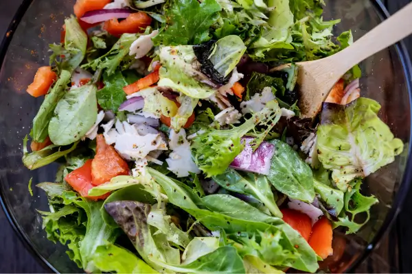Tigela com salada colorida e fresca, repleta de vegetais vibrantes, pronta para acompanhar uma refeição saudável com uma boa história à mesa.