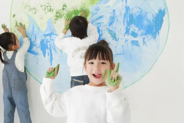 Crianças pintando juntas uma tela gigante ao ar livre, em uma atividade colaborativa que transforma o espaço externo em um estúdio de arte criativo e vibrante.