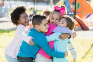 Crianças se abraçando felizes durante atividades ao ar livre, fortalecendo amizades e conexão com a natureza."