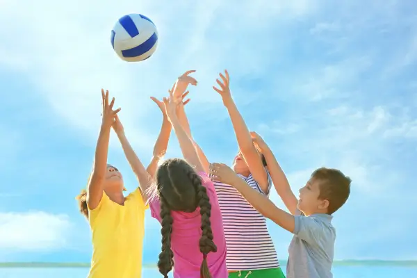 Crianças brincando no quintal com uma bola durante atividades ao ar livre, se divertindo em contato com a natureza.